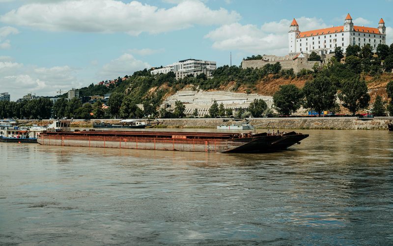 Cargo vessel on the Danube with Bratislava Castle in the background — river transport